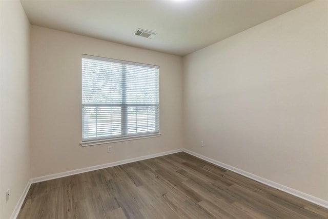 unfurnished room featuring visible vents, baseboards, and wood finished floors