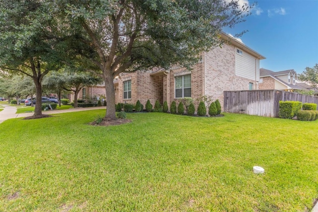 view of front of house featuring fence, a front lawn, and brick siding