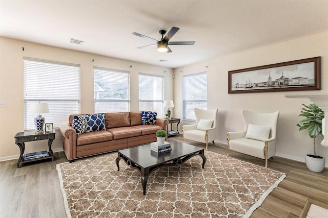 living room featuring baseboards, ceiling fan, visible vents, and wood finished floors