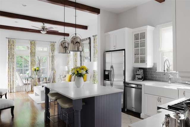 kitchen featuring stainless steel appliances, a center island, white cabinets, and beam ceiling