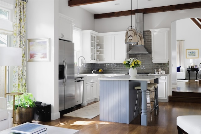 kitchen featuring stainless steel appliances, a kitchen island, white cabinetry, beam ceiling, and hardwood / wood-style floors