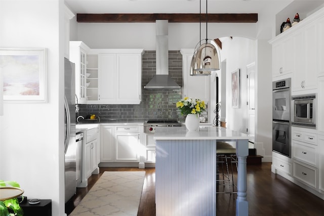 kitchen with white cabinets, wall chimney exhaust hood, dark hardwood / wood-style floors, a kitchen island, and pendant lighting