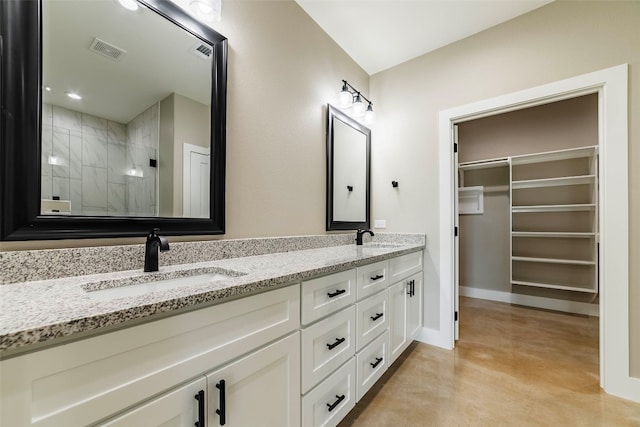 bathroom featuring concrete floors, vanity, and tiled shower