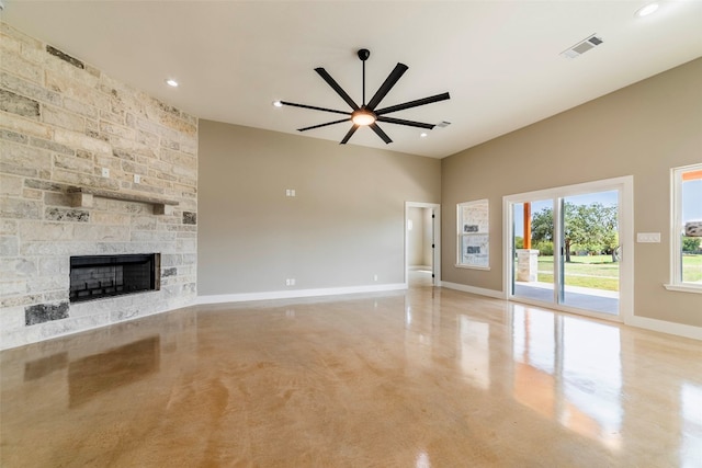 unfurnished living room with ceiling fan and a stone fireplace