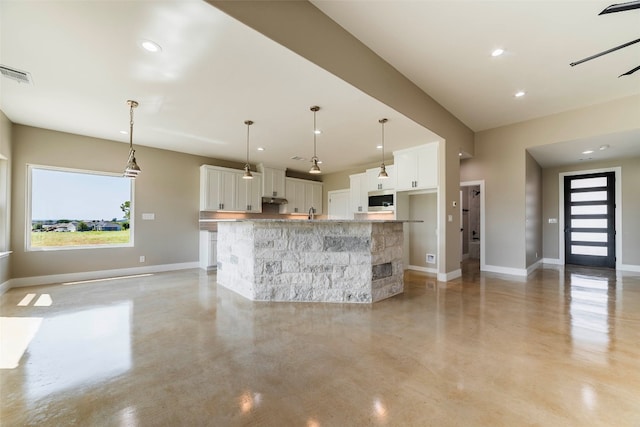 kitchen featuring light stone countertops, a kitchen island, decorative light fixtures, and white cabinetry