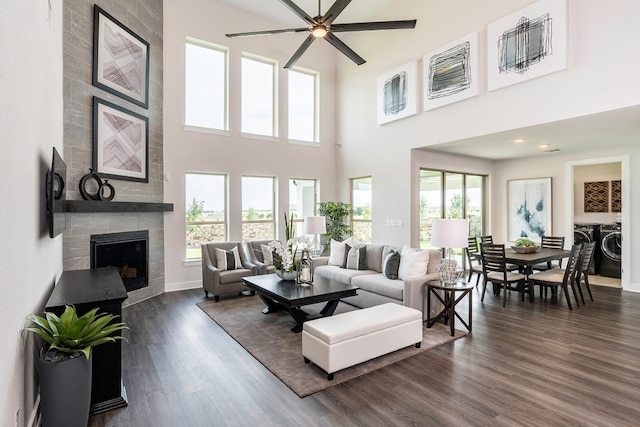 living room featuring a tile fireplace, dark hardwood / wood-style flooring, washing machine and dryer, and ceiling fan