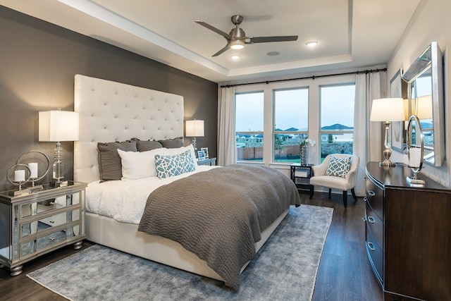 bedroom featuring a raised ceiling, ceiling fan, and dark hardwood / wood-style floors