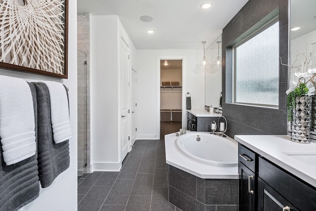 bathroom with tile patterned floors, tiled bath, and vanity