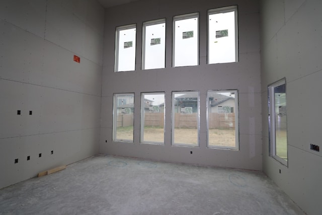 spare room with a towering ceiling and concrete floors