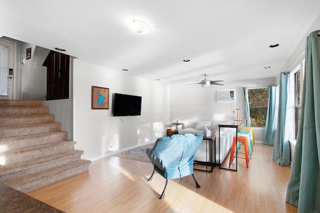 interior space featuring light wood-type flooring, a wall unit AC, and ceiling fan