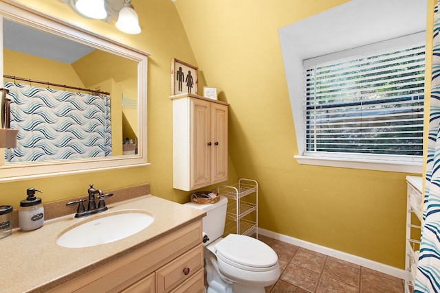 bathroom with tile patterned flooring, toilet, vaulted ceiling, and vanity