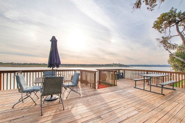 deck at dusk featuring a water view