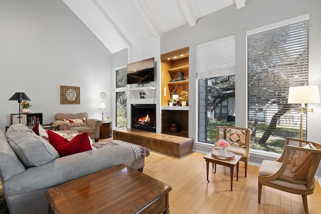 living room with light hardwood / wood-style flooring, beam ceiling, and high vaulted ceiling