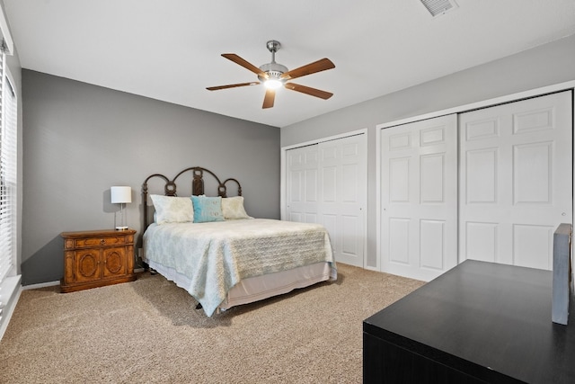 carpeted bedroom with multiple closets and ceiling fan