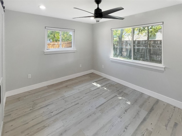 spare room with light wood-type flooring, plenty of natural light, and ceiling fan