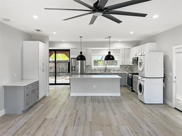 9614 Newfoundland Cir, Austin, TX 78758 - kitchen featuring estacked washer and dryer, stainless steel appliances, a ceiling fan, tasteful backsplash, and plenty of natural light