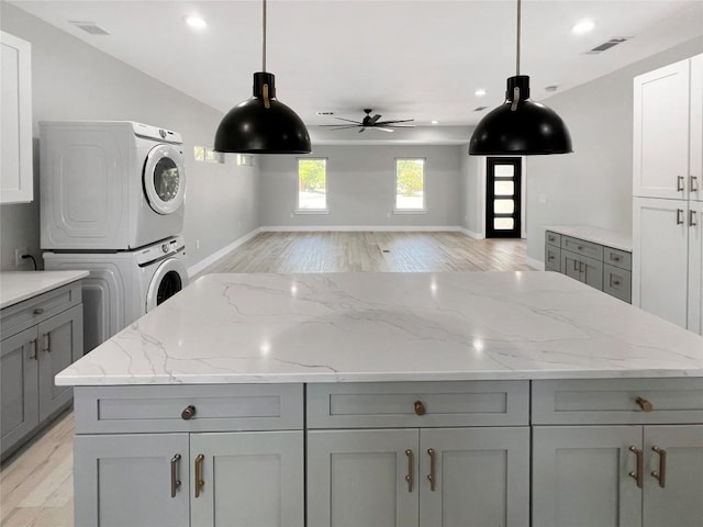 9614 Newfoundland Cir, Austin, TX 78758 - kitchen with stacked washer and clothes dryer, gray cabinetry, a ceiling fan, light wood-style floors, and recessed lighting