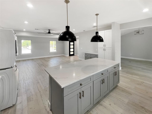 9614 Newfoundland Cir, Austin, TX 78758 - kitchen featuring stacked washer and clothes dryer, gray cabinetry, ceiling fan, a kitchen island, and recessed lighting