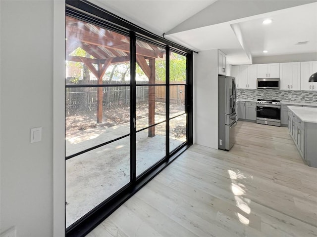 9614 Newfoundland Cir, Austin, TX 78758 - kitchen with stainless steel appliances, tasteful backsplash, light countertops, gray cabinetry, and light wood-type flooring