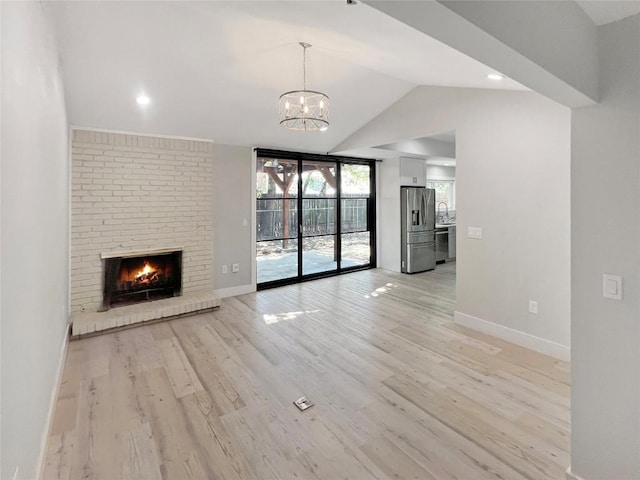 9614 Newfoundland Cir, Austin, TX 78758 - unfurnished living room featuring vaulted ceiling, light wood-type flooring, a chandelier, and a brick fireplace