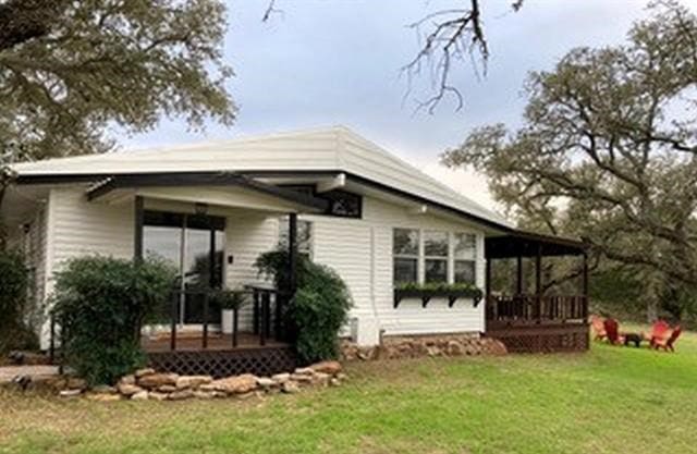 rear view of property featuring a yard and a wooden deck