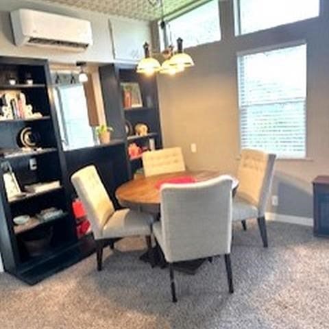 carpeted dining space with an AC wall unit