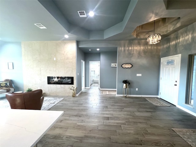 interior space featuring a tray ceiling, wood-type flooring, a fireplace, and an inviting chandelier