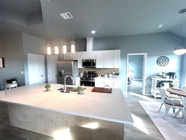 kitchen with appliances with stainless steel finishes, pendant lighting, an island with sink, and sink