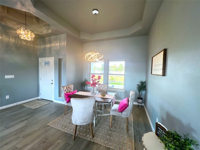 dining room with a raised ceiling, a chandelier, a high ceiling, and dark hardwood / wood-style floors