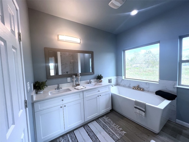 bathroom featuring vanity, plenty of natural light, wood-type flooring, and a bathtub