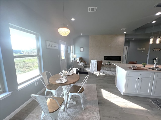 dining space featuring lofted ceiling, a fireplace, light hardwood / wood-style floors, and sink