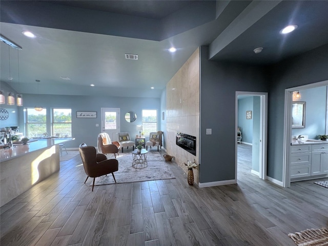 living room featuring a tiled fireplace and light wood-type flooring