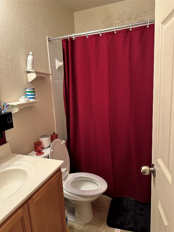 bathroom featuring tile patterned floors, walk in shower, toilet, and vanity