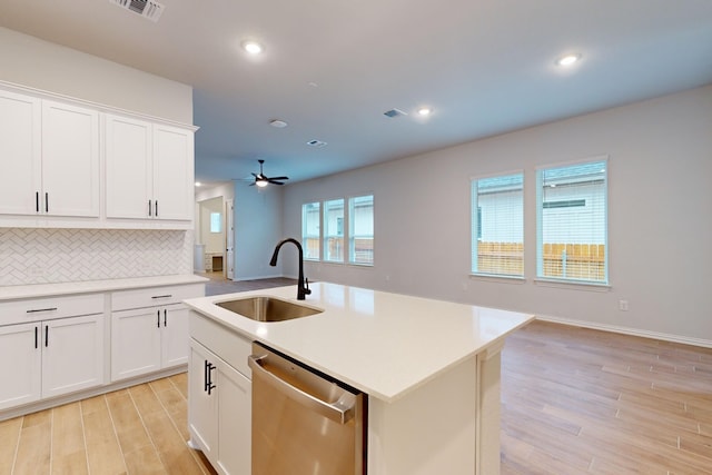 kitchen featuring white cabinets, stainless steel dishwasher, a kitchen island with sink, and sink