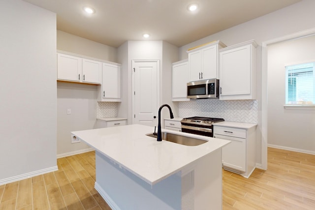 kitchen with a kitchen island with sink, sink, white cabinets, and stainless steel appliances