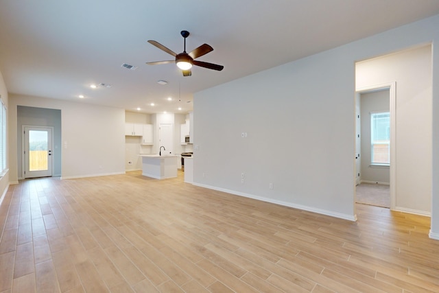 unfurnished living room with ceiling fan, light hardwood / wood-style flooring, and sink