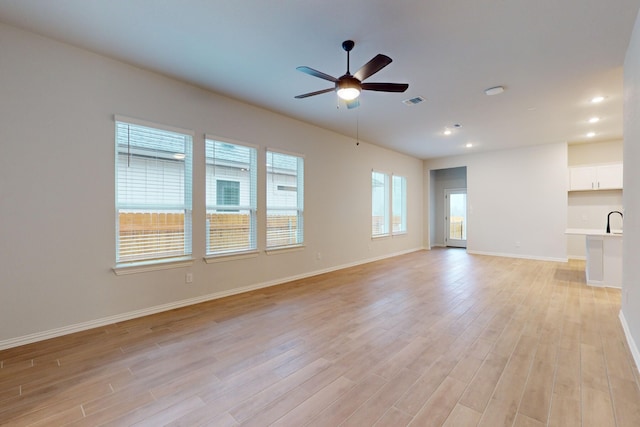 unfurnished living room with light hardwood / wood-style flooring, ceiling fan, and sink