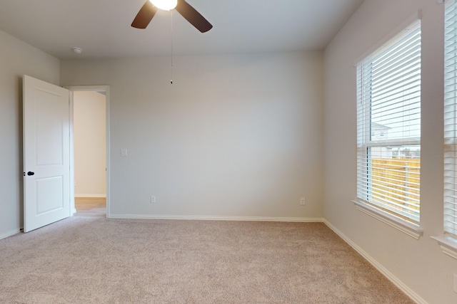 carpeted empty room with ceiling fan and a wealth of natural light