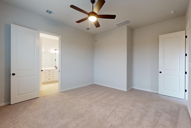 unfurnished bedroom with ceiling fan, light carpet, and connected bathroom