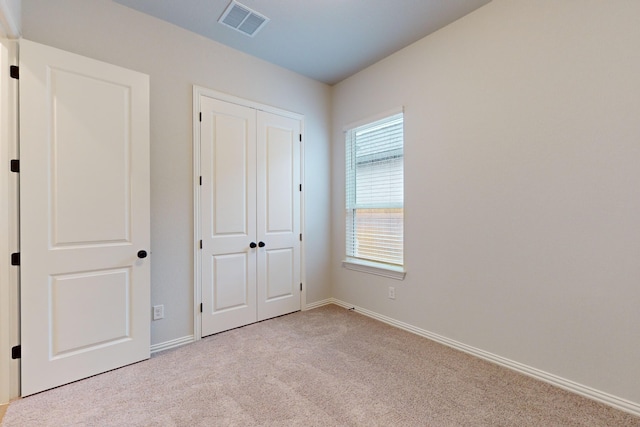 unfurnished bedroom featuring a closet and light colored carpet