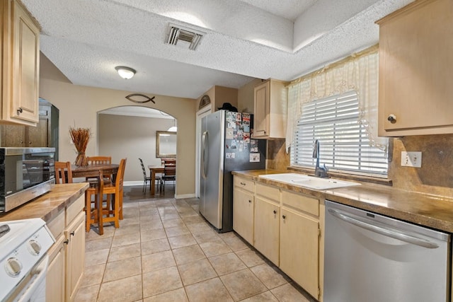 kitchen with light tile patterned floors, stainless steel appliances, a textured ceiling, and sink