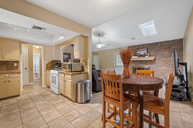 dining area with ceiling fan, a fireplace, light tile patterned flooring, and a textured ceiling