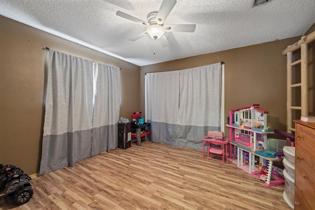 playroom with a textured ceiling, wood-type flooring, and ceiling fan