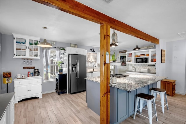 kitchen with decorative light fixtures, appliances with stainless steel finishes, light stone countertops, and white cabinetry