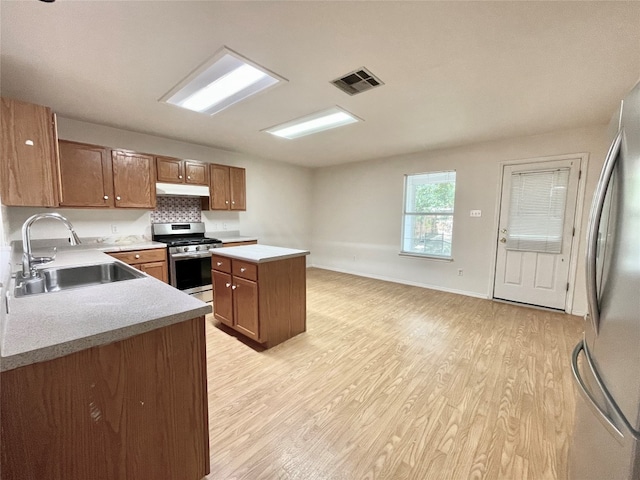 kitchen featuring appliances with stainless steel finishes, a kitchen island, sink, and light hardwood / wood-style floors