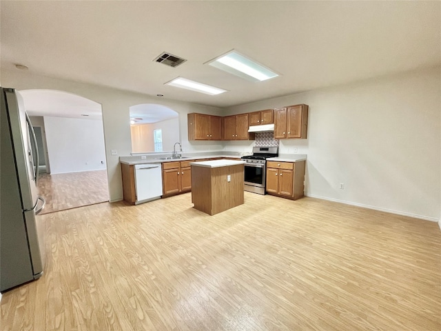 kitchen featuring light wood-type flooring, appliances with stainless steel finishes, a center island, and sink