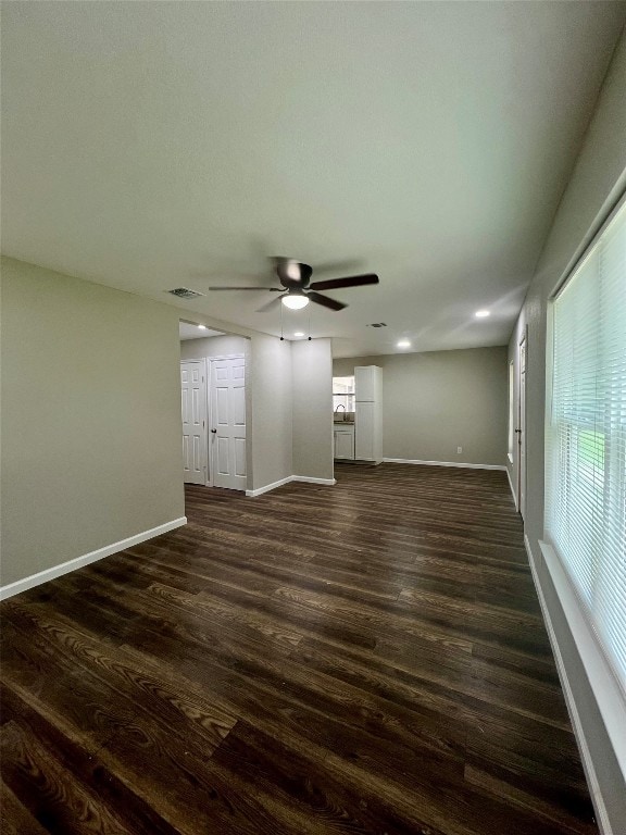 unfurnished living room with dark wood-type flooring and ceiling fan