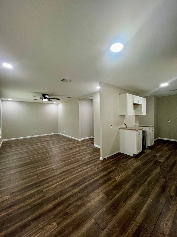 unfurnished living room featuring dark wood-type flooring and ceiling fan