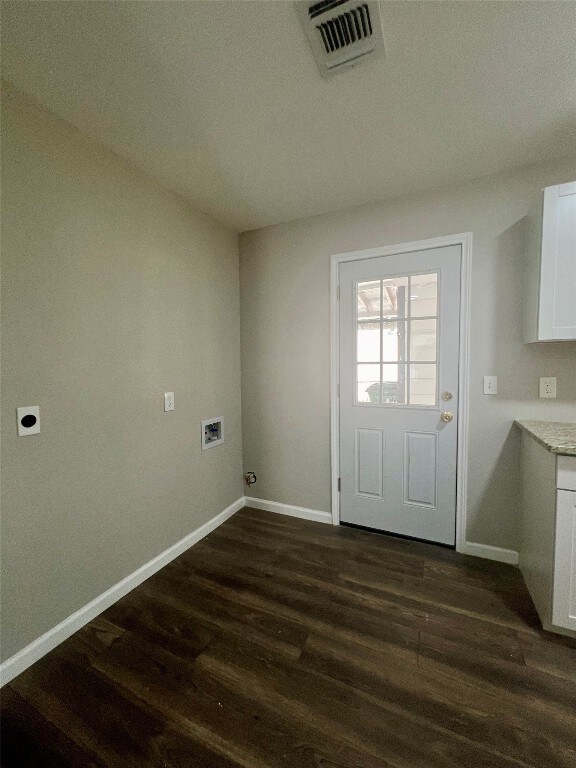 washroom with dark wood-type flooring, hookup for a washing machine, hookup for an electric dryer, and cabinets