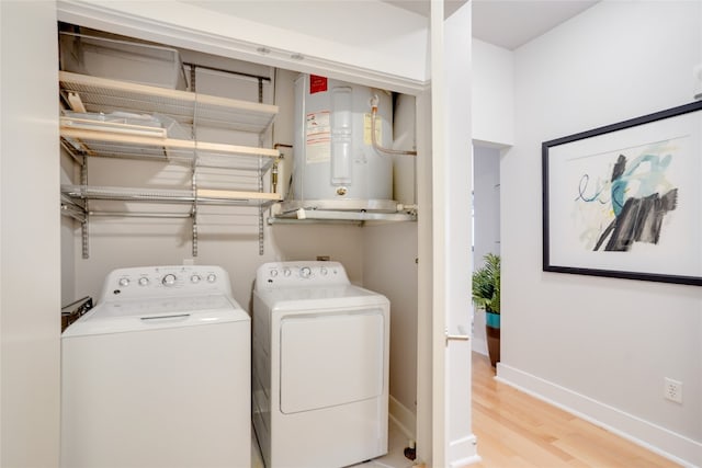 laundry room with light wood-type flooring, independent washer and dryer, and electric water heater